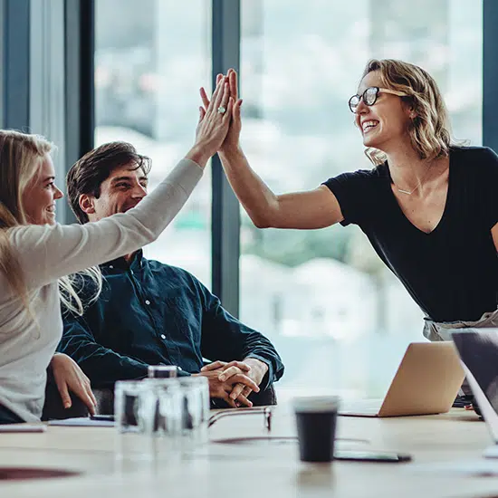 IT team celebrating success with a high five during a business meeting