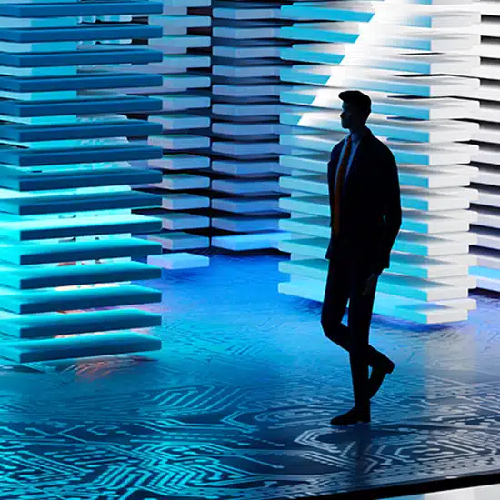 A person walking through an abstract data center with a circuit board floor and walls made of data stacks
