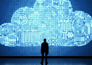 Silhouette of a person gazing at a cloud-shaped circuit board, representing cloud technology.