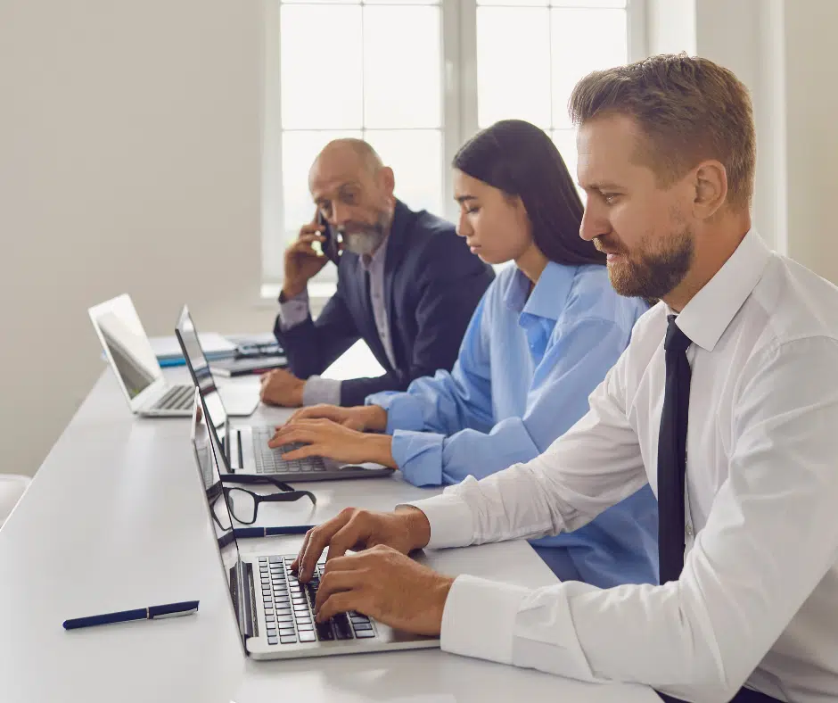 Team of outsourced IT professionals at a shared desk space, typing and taking phone calls